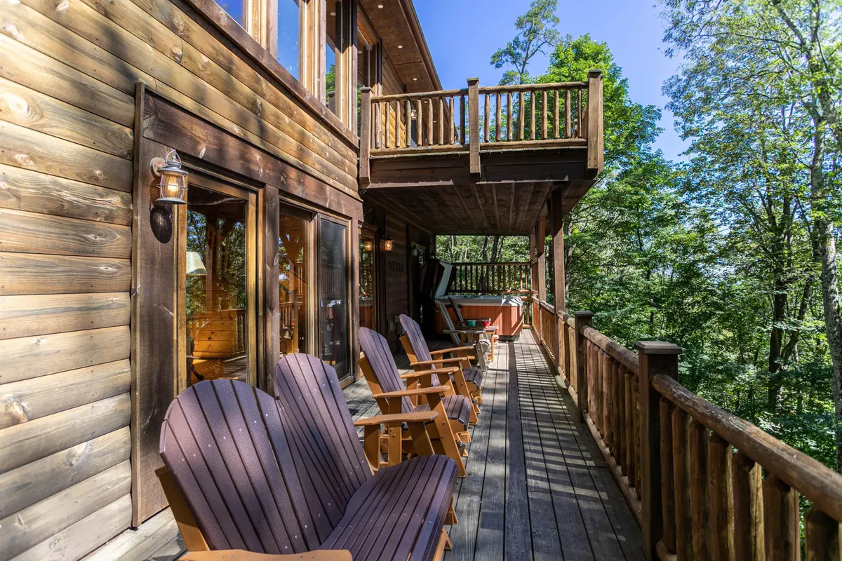 The image shows a wooden balcony furnished with comfortable chairs, overlooking a scenic natural landscape. The view captures lush greenery and gives a sense of peaceful seclusion, inviting guests to relax outdoors and enjoy the surrounding environment.