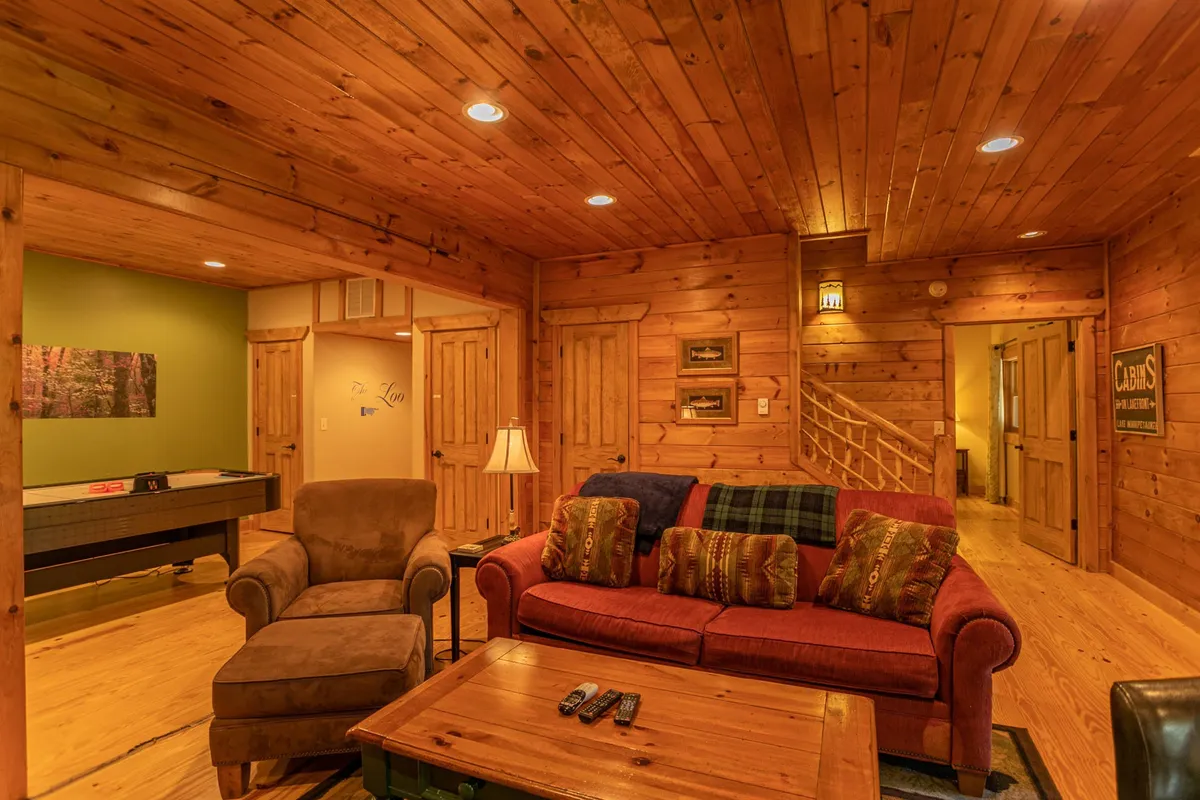 A cozy interior with a red sofa, wooden walls, soft lighting from lamps, and a pool table. The space feels open and inviting, evoking the sense of gathering after a day spent exploring outside.